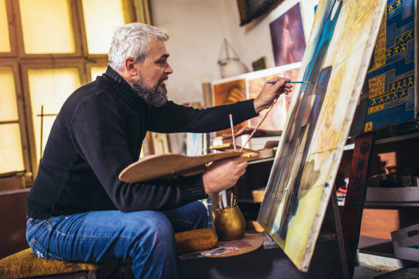 istock Mature man painting on canvas in art studio. 1310905280