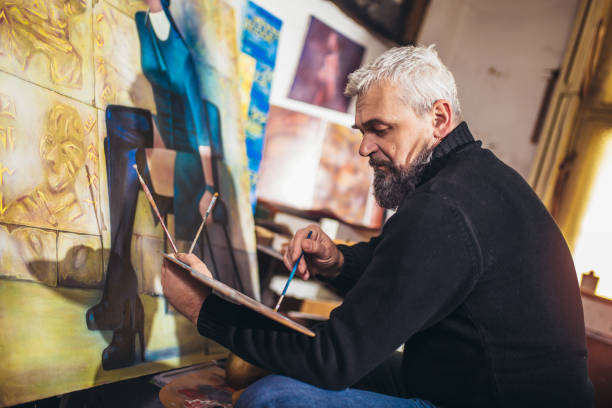 istock Mature man painting on canvas in art studio. 1310907902