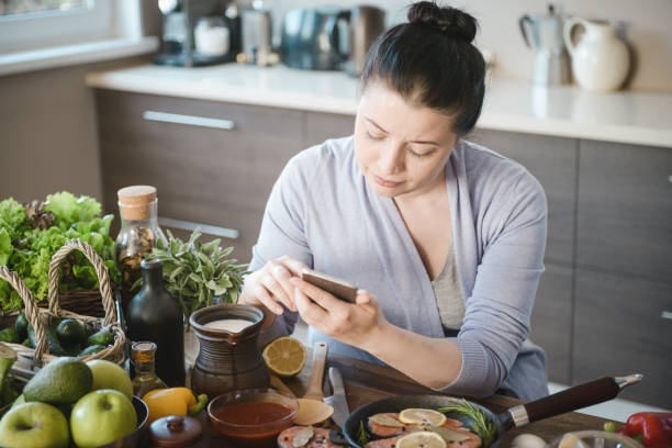 istock woman cooking in the kitchen ( with fish salmon, smart phone) 1310907905