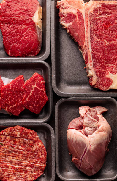 istock Black plastic packaging trays from supermarket with different types of fresh raw meat cuts, fresh beefbeef steaks and variety meats in boxes from above 1310910404