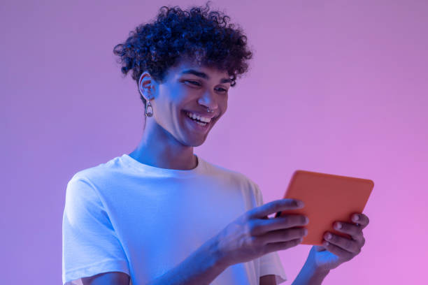 istock Curly-haired young guy holding a tablet and looking involved 1310911320