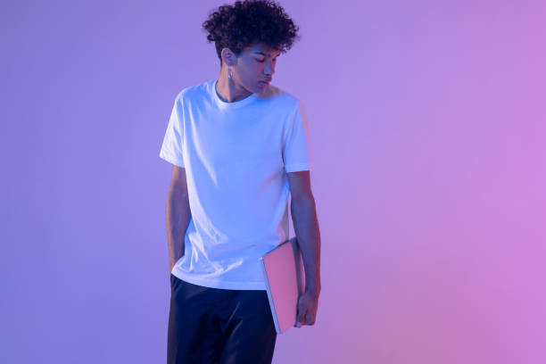 istock Curly-haired young guy in white tshirt with a laptop 1310911324
