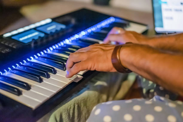 Close-up shot of an unrecognizable Indian musician playing keyboard at home.