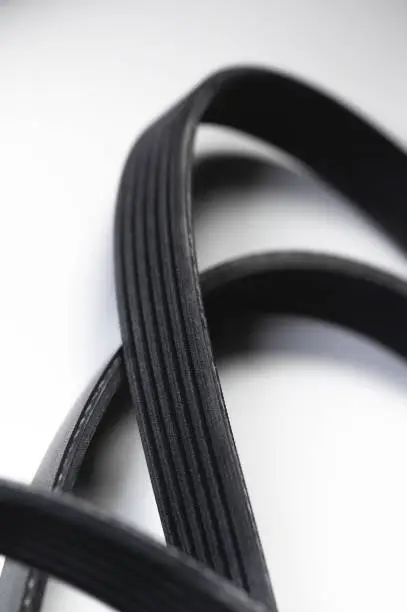 Close-up of a poly V-belt of a generator on a gray background in shallow depth of field. Background for rubber products of auto parts.