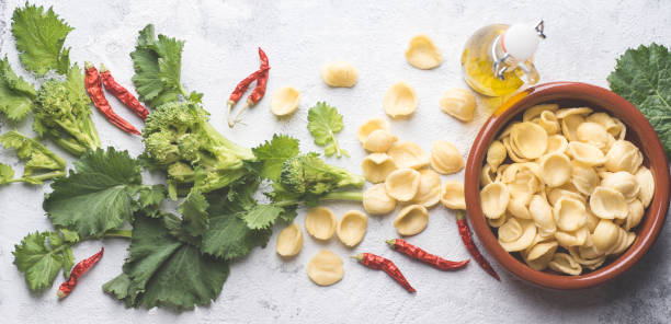 orecchiette di pasta italiana fatte a mano con foglie e cime di rapa o cima di rapa con aglio, peperoncino, olio d'oliva su sfondo bianco testurno. ricette e ingredienti del sud italia, puglia - orecchiette foto e immagini stock