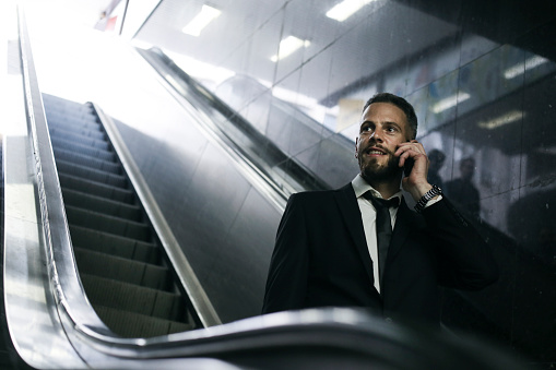 Mid adult businessman going on an escalator at a subway station. About 35 years old, Caucasian male.