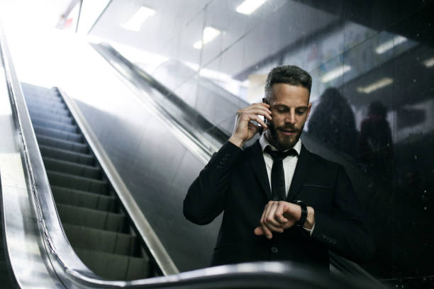 Hurry to work Mid adult businessman going on an escalator at a subway station. About 35 years old, Caucasian male. smart watch business stock pictures, royalty-free photos & images