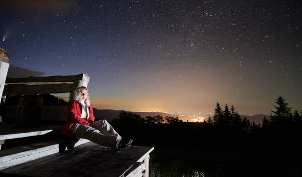 istock Beautiful young woman sitting under night starry sky. 1310912095