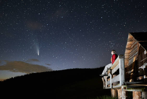 istock Young woman sitting under beautiful night sky with stars. 1310912126