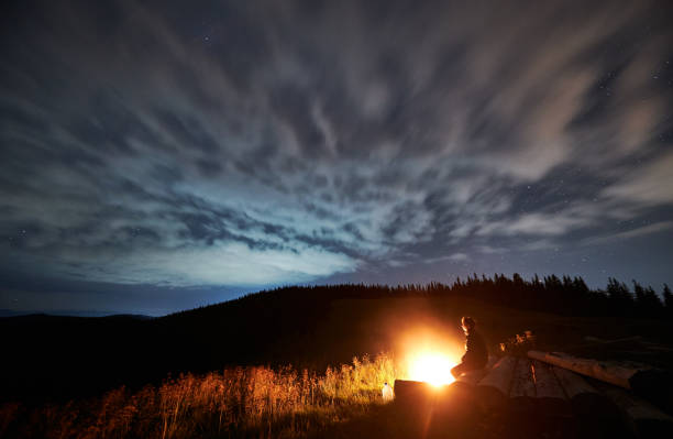 istock Wide angle view on cloudy starry night in the mountains and a man enjoying nature 1310912143