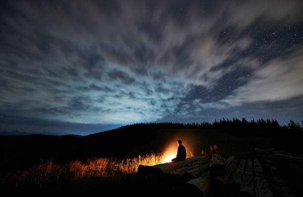 istock Man is sitting on decks near bonfire in mountains. 1310912151