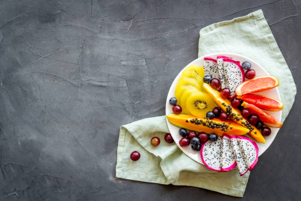 istock Mix of tropical fruit in white plate. Overhead view 1310915914