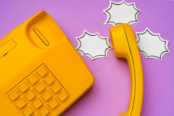 istock Yellow landline phone with speech bubble on purple background 1310916565