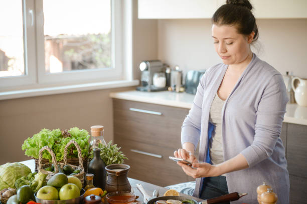 istock woman cooking in the kitchen ( with fish salmon, smart phone) 1310916606