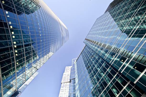 istock Bottom-up view of modern office buildings on bright clear blue sky background 1310918724