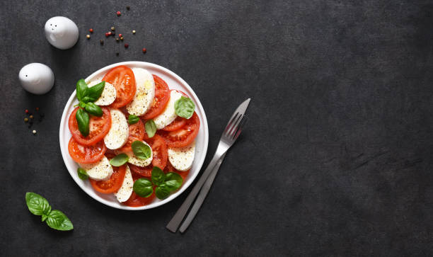 caprese es un aperitivo de tomate y mozzarella. ensalada tradicional italiana sobre un fondo negro con espacio para texto. vista desde arriba. - mozzarella caprese salad tomato italian cuisine fotografías e imágenes de stock