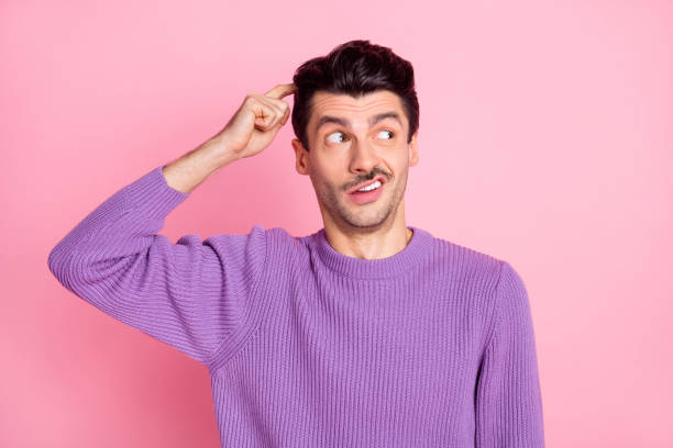 istock Photo of charming unsure young man dressed purple pullover forget something finger head isolated pink color background 1310919984