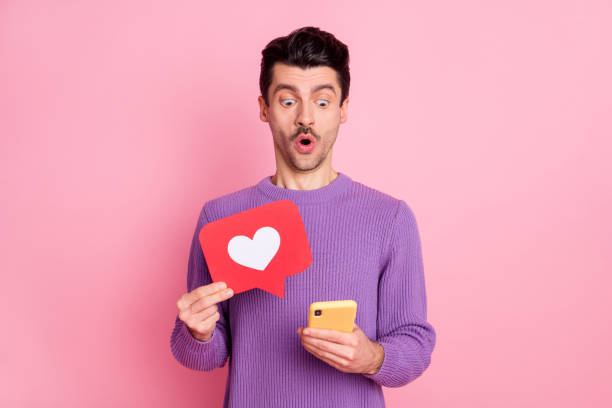 istock Portrait of attractive amazed guy using device browsing holding like card isolated over pink pastel color background 1310920088