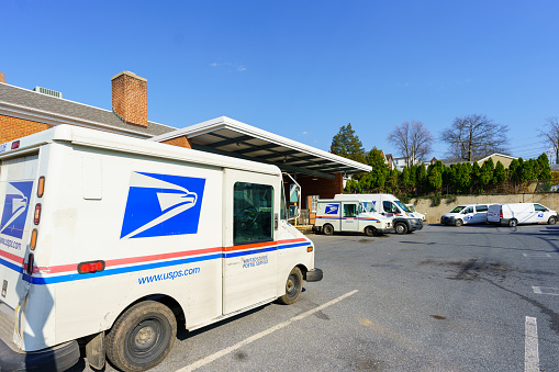 Ephrata, PA, USA - April 4, 2021: USPA Mail delivery trucks parked at the Ephrata Post Office in Lancaster County, PA.