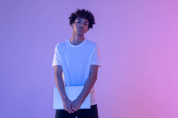 istock Curly-haired young guy in white tshirt with a laptop 1310925965