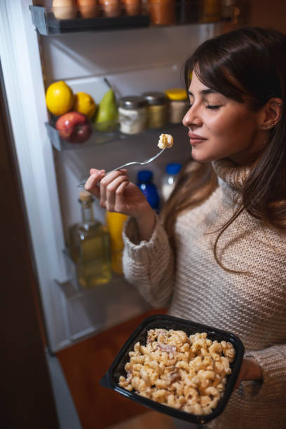 istock Woman enjoying eating at night by opened fridge 1310926271