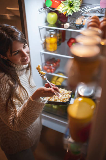 istock Woman eating next to an opened fridge 1310926286
