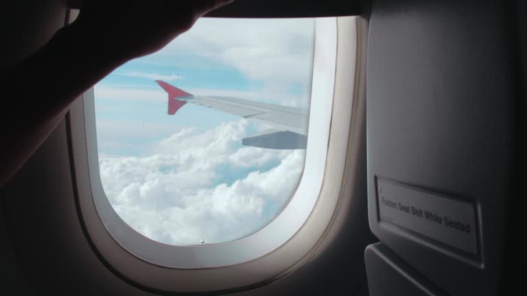 Open the window on airplane through see the sky and clouds