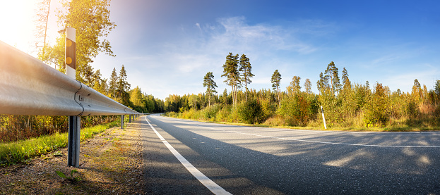 Asphalt road panorama in countryside in summer. Route with white dividing lines and guard rails in beautiful nature landscape.