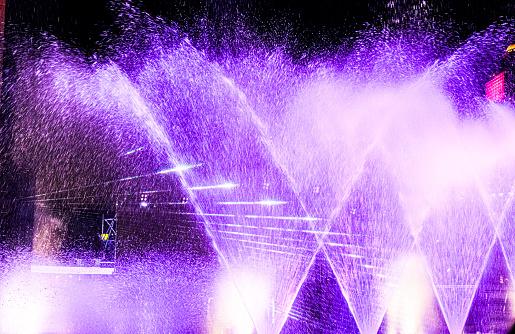 illumina night water light party spray on sky. festival show musical concert. beautiful purple sparkle effect.