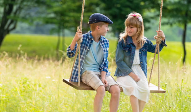 istock Boy And Girl Sitting On Swing In Forest 1310934215