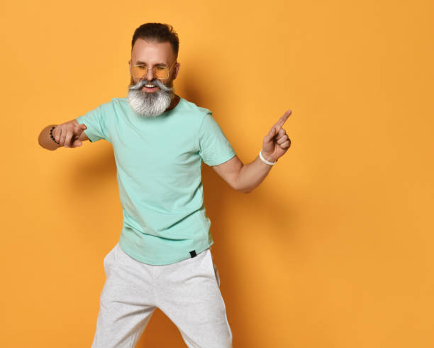 istock Stylish trendy gray-haired hipster guy dancing and having fun on bright orange background 1310935181