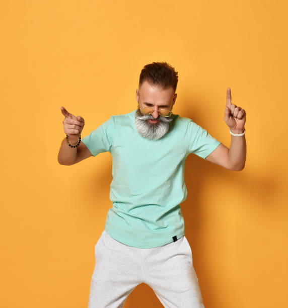 istock Stylish trendy gray-haired hipster guy dancing and having fun on bright orange background 1310935890
