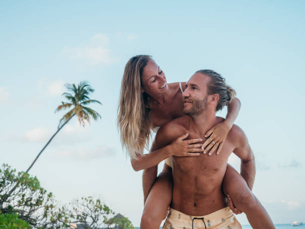 istock Handsome young man giving piggyback ride to girlfriend on beach. 1310940688