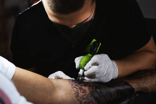 istock Tattoo Artist making a tattoo on a hand in tattoo studio 1310943780