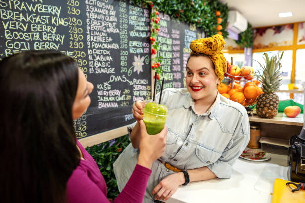 Smiling young bar employees tasteing new fresh fruit juice.