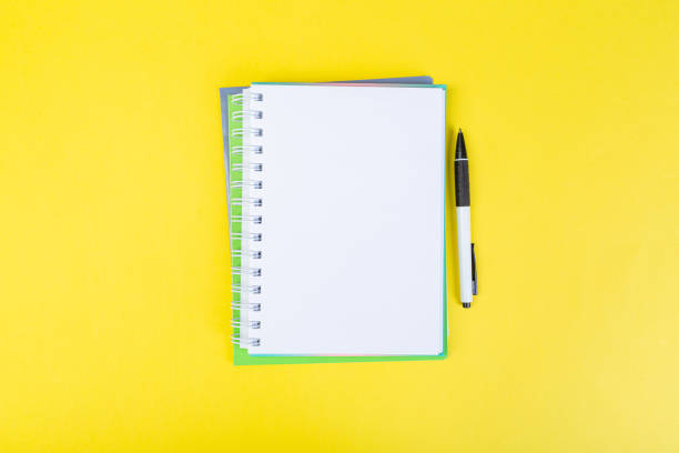 istock open spiral notepad on a yellow background with a pen. top view, stack of notepad with blank sheet. school concept, businessman work desk. 1310944173