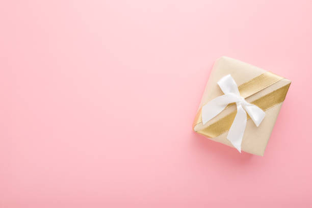 istock Beige paper gift box with white ribbon on light pink table background. Pastel color. Congratulation concept. Empty place for emotional, sentimental text, positive quote or cute sayings. Top down view. 1310946069