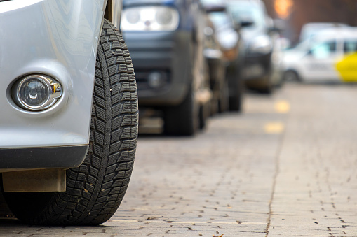 Closeup of parked car on a city street side with new winter rubber tires.