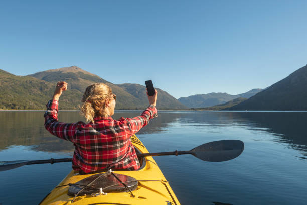 Beautiful woman Enjoying the lakes in her yellow kayak for her summer vacation trip through Patagonia.