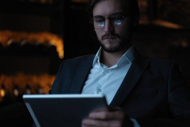 istock Businessman working using tablet computer while sitting in cafe late at night in front of windows overlooking the city. 1310949071