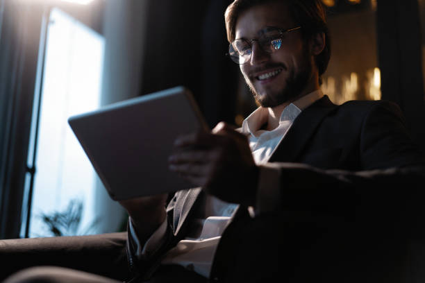 istock Businessman working using tablet computer while sitting in cafe late at night in front of windows overlooking the city. 1310949076