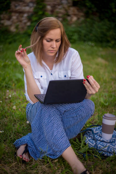 istock Female professional working on laptop while sitting on park 1310950122