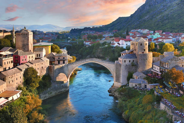 Skyline of Mostar with the Mostar Bridge, houses and minarets, at the sunset in Bosnia and Herzegovina. Historical Mostar Bridge at the sunset in Mostar, Bosnia and Herzegovina mostar stock pictures, royalty-free photos & images