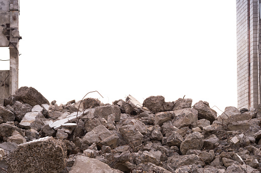 A pile of construction debris and large concrete wreckage against the background of a destroyed building in the form of a border frame and a gray sky. Background.