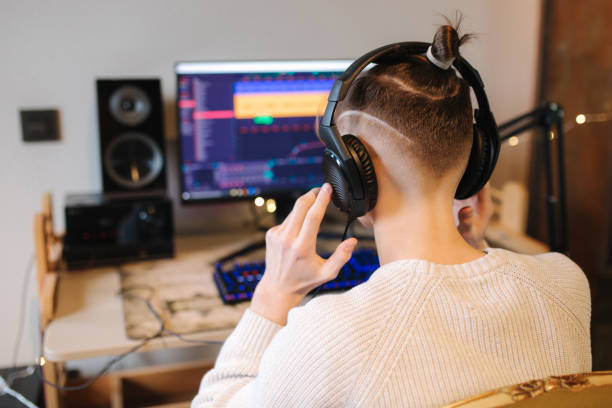 istock Handsome guy is recording podcast using microphone and creating content for audio blog. Man put on headphones and starting work at home. Sound equipment concept. Back view 1310951919