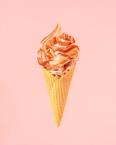 Minimal  composition with ice cream cone full of fresh bacon against pastel pink background. Creative summer bbq concept.