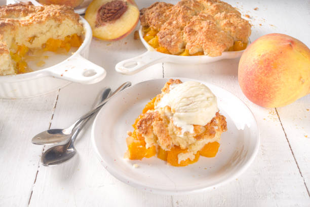 Delicious Homemade Peach Cobbler Delicious Summer Peach Cobbler, Homemade sweet summer pie with peaches and vanilla ice cream on white wooden background copy space cobbler dessert stock pictures, royalty-free photos & images