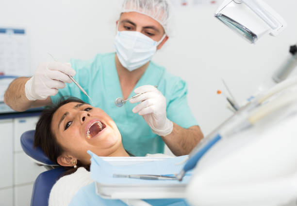 istock Dentist man examining a latin female patient teeth 1310958165