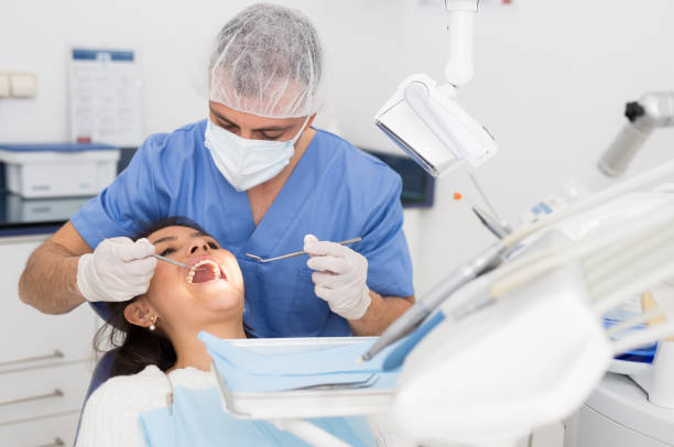 istock Dentist man examining a latin female patient teeth 1310958167