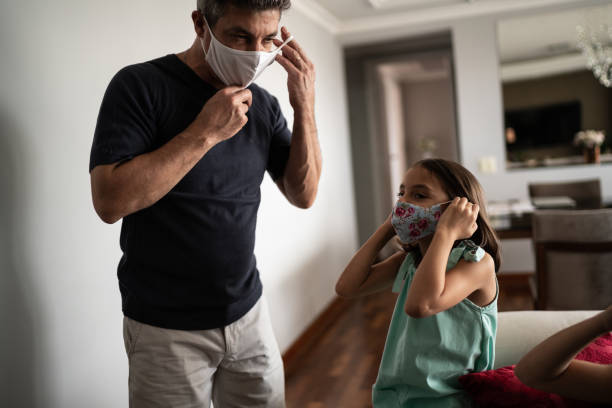 istock Father and daughter putting on face mask at home 1310961365